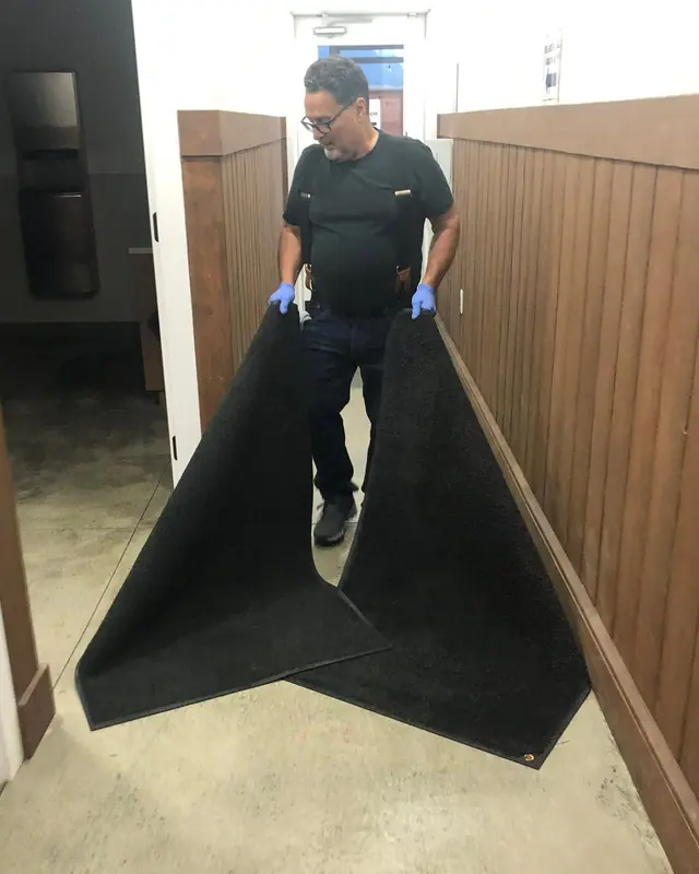Cleaning Technician handling entrance mats during a commercial cleaning visit