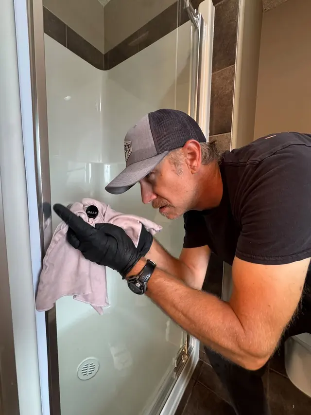 Cleaning Technician cleaning a glass shower door