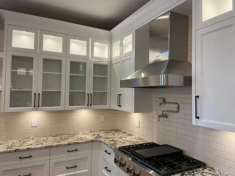 Clean kitchen with white cabinets and a stainless range hood